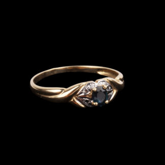 18K gold ring with dark blue oval faceted stone in claw setting